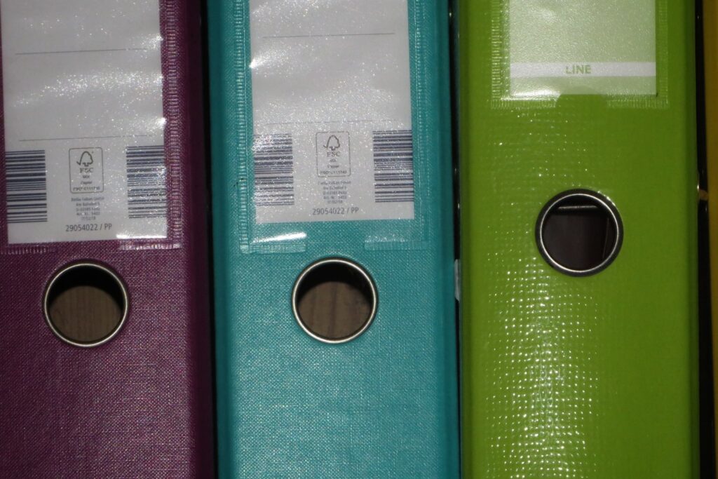 a row of colored binders on a shelf