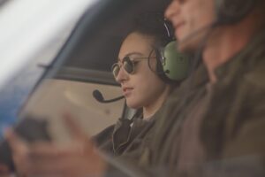 Two people in a helicopter cockpit wearing headsets